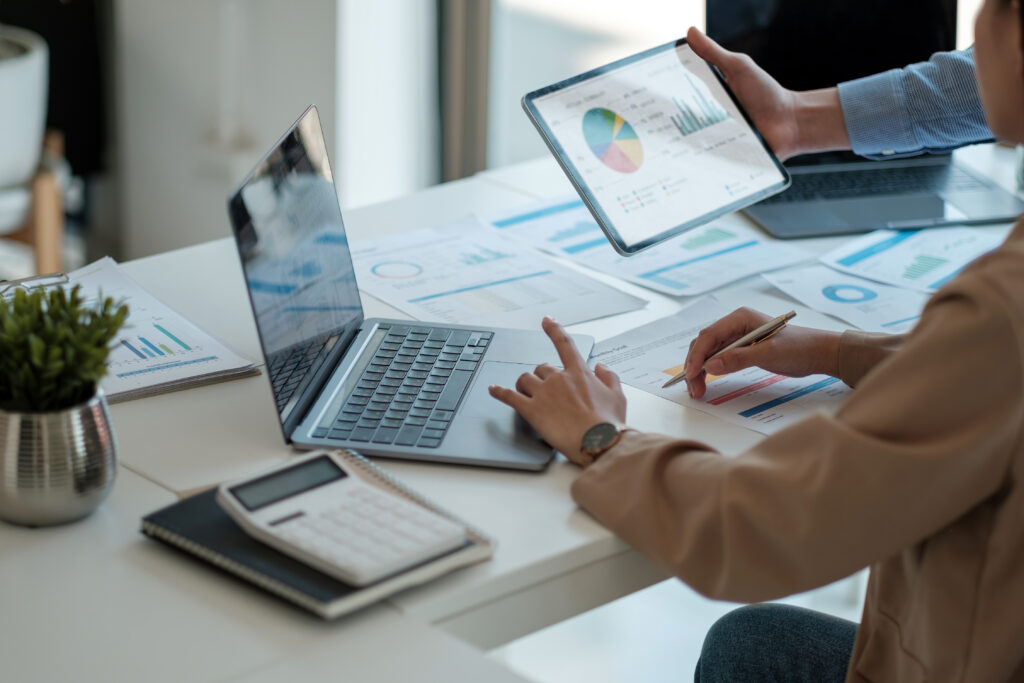 Mesa de trabalho com notebooks, calculadora e relatórios financeiros